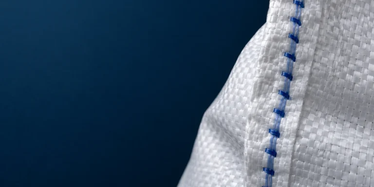 Editorial illustration of white polypropylene woven-sack fabric and a blue stitched seam